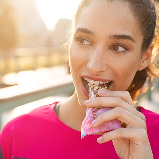 Eiweissreiche Snacks enthalten Aminosäuren Frau beisst in eiweissreichen Snack