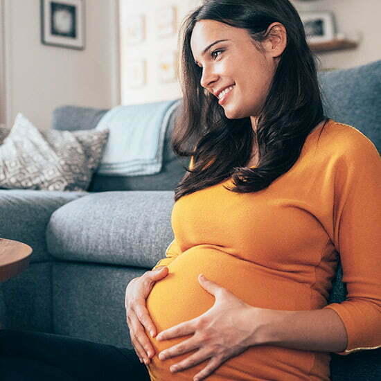 Während Schwangerschaft und Stillzeit auf Omega-3-Zufuhr achten Schwangere Frau hält sich den Bauch.