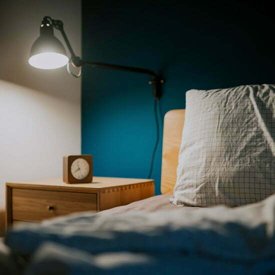 Melatonin bestimmt den Schlafrhythmus Nachttischlampe, Wecker und Bett