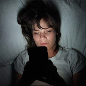 Frau benutzt Ihr Handy im Bett