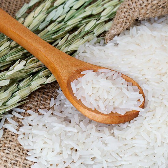 Aus Reis entsteht ein beliebtes Proteinpulver Ungekochter Reis auf Holzlöffel