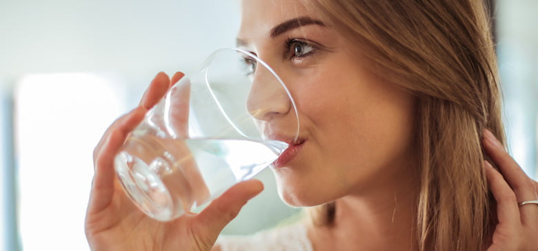 Wieviel Wasser trinken hilft? Frau trinkt Wasser