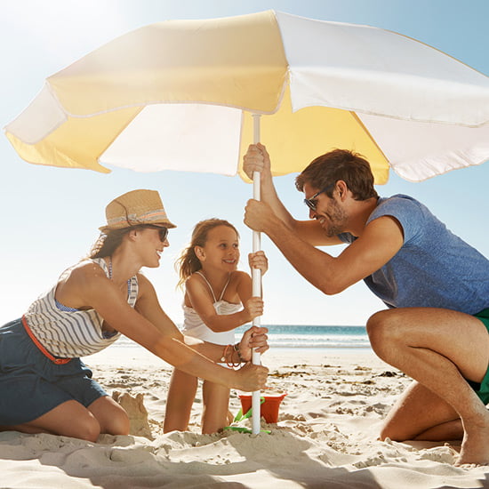 Ein Sonnenschirm schützt die ganze Familie Familie unter Sonnenschirm